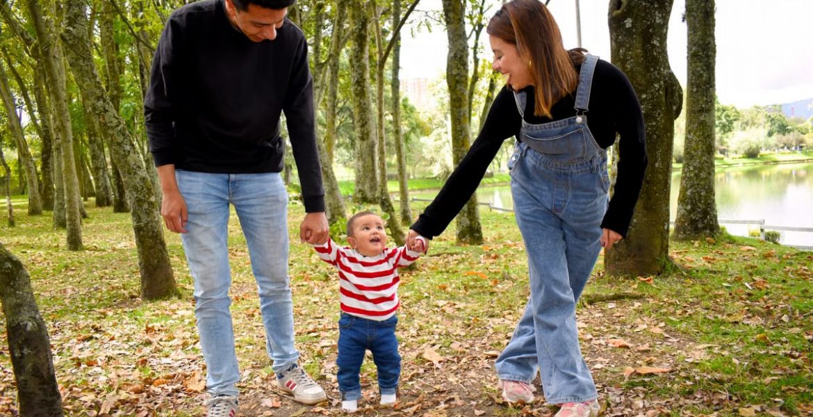 A joyful family enjoys a walk under lush green trees in the park.