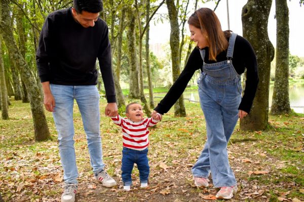 A joyful family enjoys a walk under lush green trees in the park.