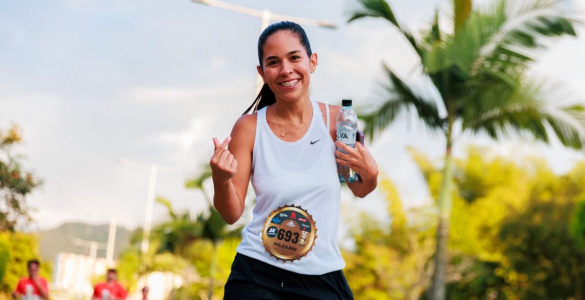 Smiling woman running a marathon outdoors in warm weather.